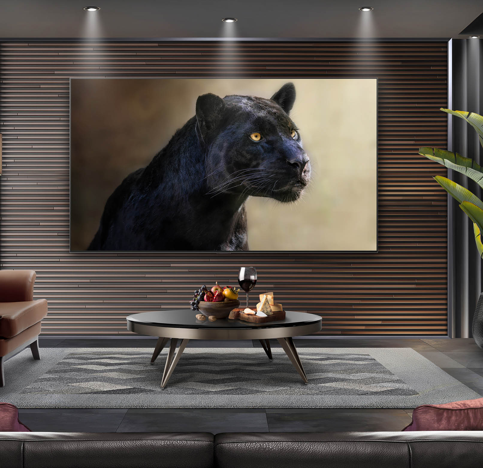 A modern living room features a large flat-screen TV mounted on a wood-paneled wall displaying a close-up image of a black panther with yellow eyes, with a coffee table holding a glass of wine, fruit, and cheese in front. Description generated by AI